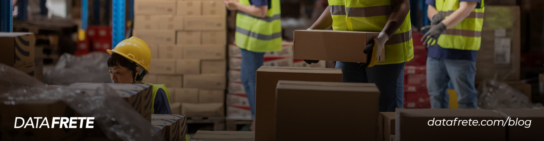 Trabalhadores com coletes de alta visibilidade e capacete organizam caixas de papelão em um armazém logístico, com o logotipo da Datafrete no rodapé.